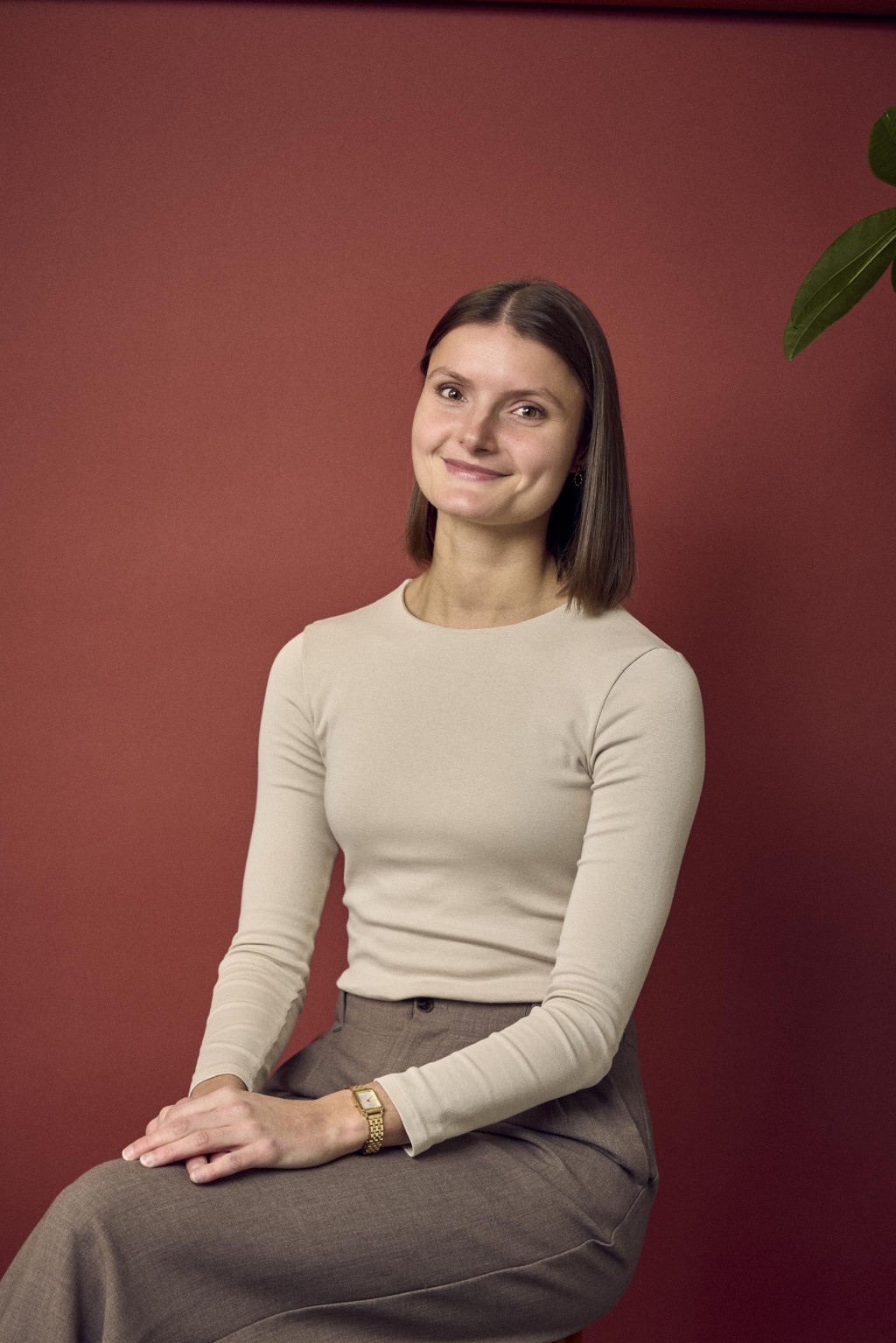Eva Huirne voor een rode backdrop met een beige lange mouwen top aan.