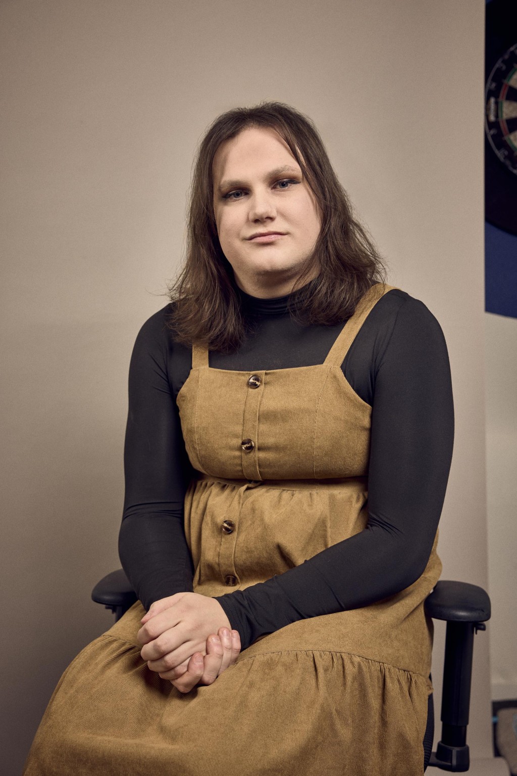 Olivia Arents voor een bronzen backdrop zittend in een bureaustoel.