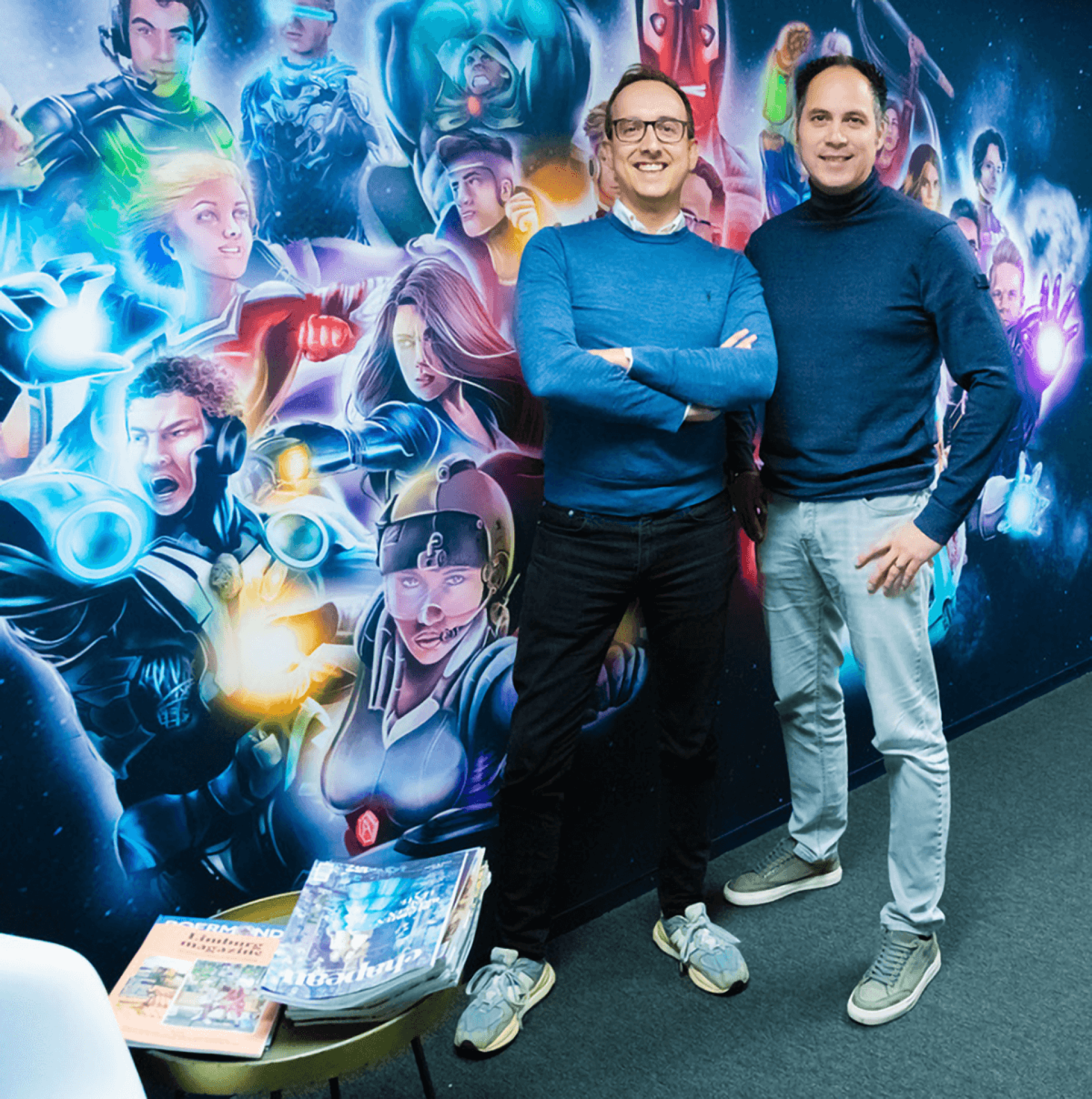 De directie van Appart Paul Cremers en Owen Manusama, voor een muur met superhelden in de hal van het kantoor.