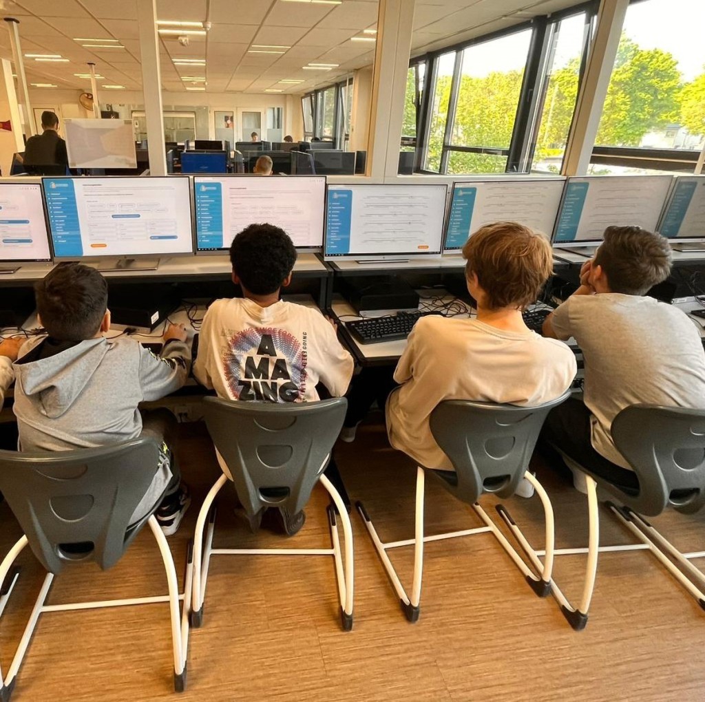 Vier studenten die allemaal op een computer op de site van Regio in je Rugzak zitten op een school.