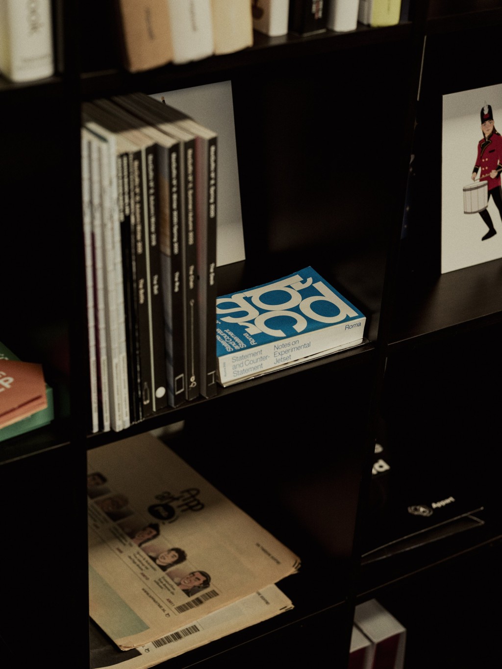 Close-up van een donkere boekenplank gevuld met design-, marketing- en inspiratieboeken in een creatieve kantooromgeving.