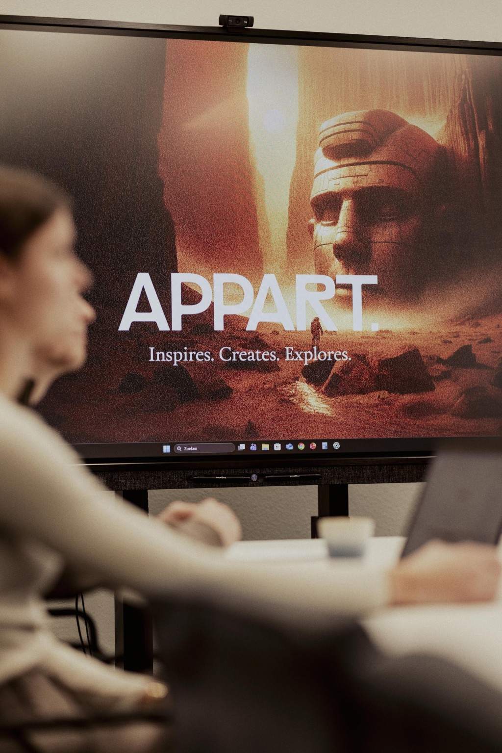 Twee mensen te zien van de zijkant tijdens een meeting, met een groot scherm waarop het logo van Appart te zien is.
